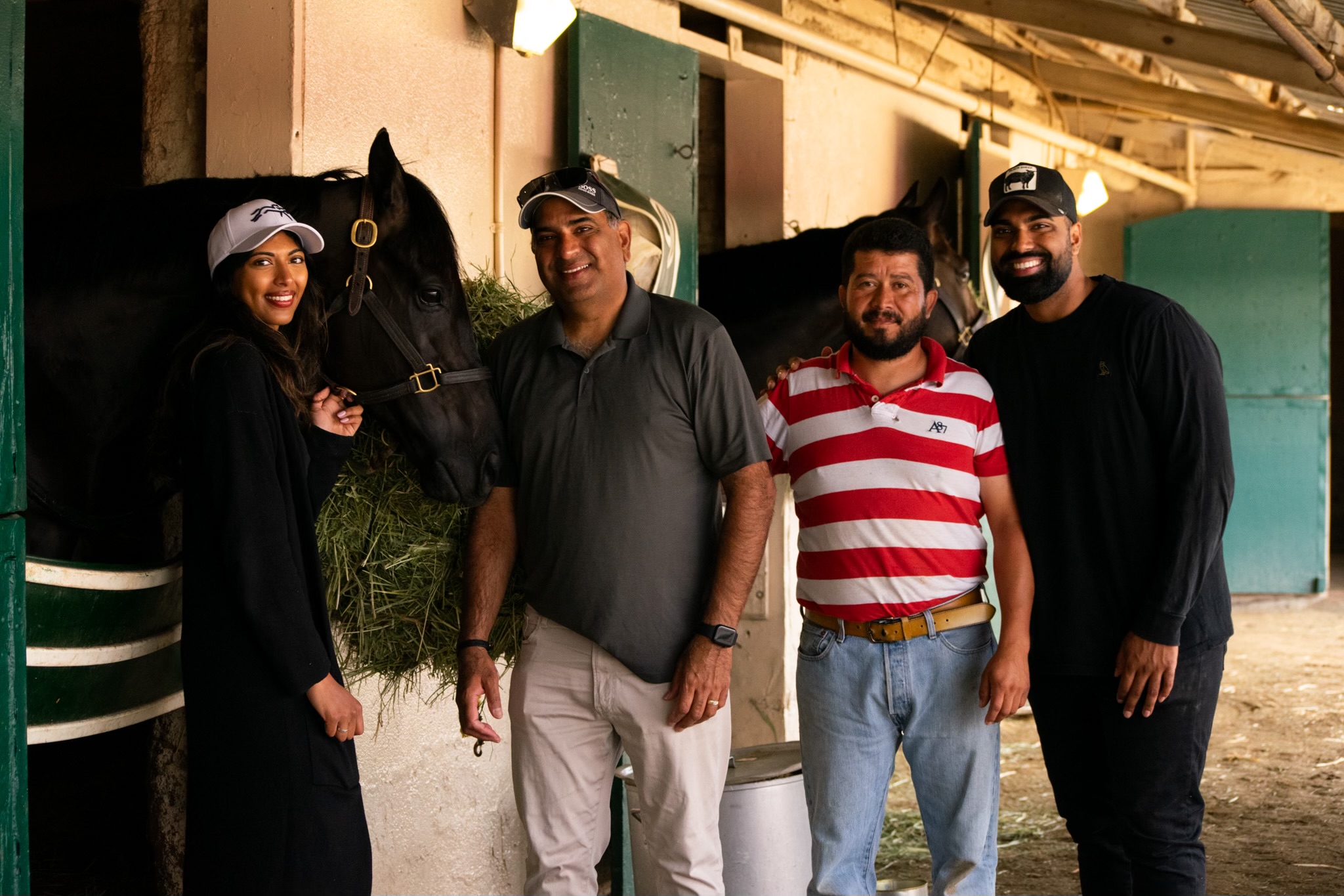 Family and stable team gathered with horses in the barn